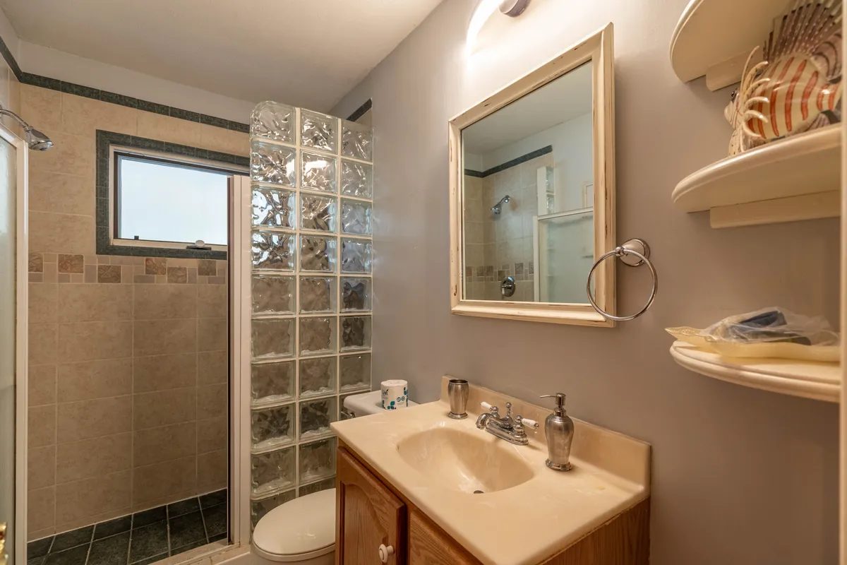 A sparkling bathroom with a glass block walk-in shower, a modern vanity with a sink, and a large framed mirror. The space feels inviting, clean, and practical—an ideal spot to refresh after active days outdoors.