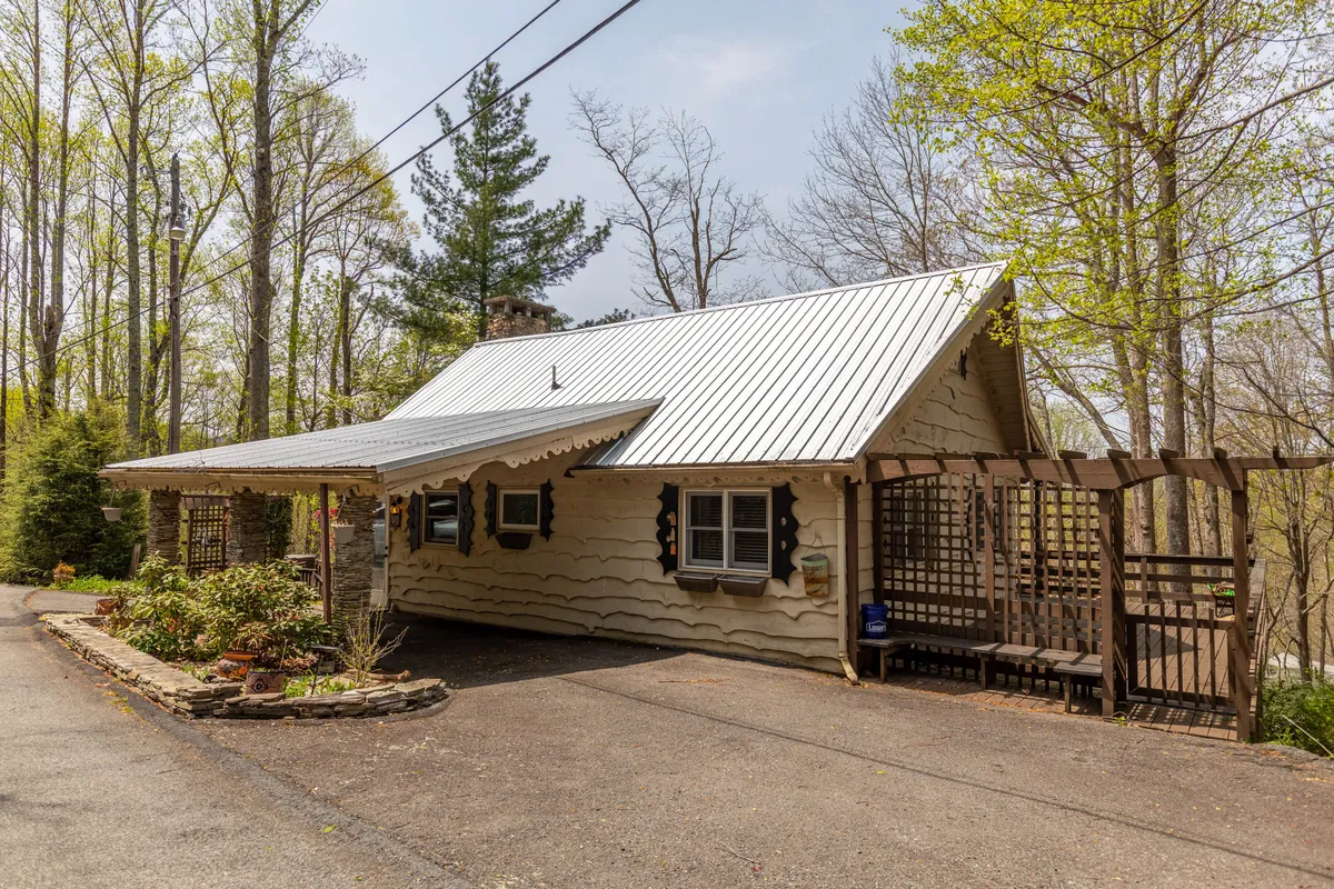 This exterior shot captures the charming cottage façade with a wooden trellis and lush greenery. The peaceful porch and vibrant landscaping set a tranquil, inviting tone, suggesting easy access to the scenic surroundings and outdoor adventures.