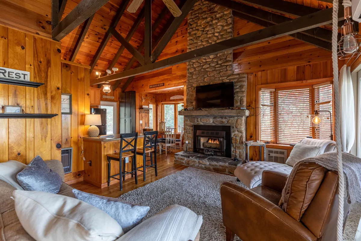 This image captures a rustic interior featuring a stone fireplace, exposed wooden beams, and cozy seating arranged for socializing. The atmosphere is warm and inviting—ideal for unwinding by the fire, sharing stories, or enjoying a game night after a day of hiking or brewery visits.