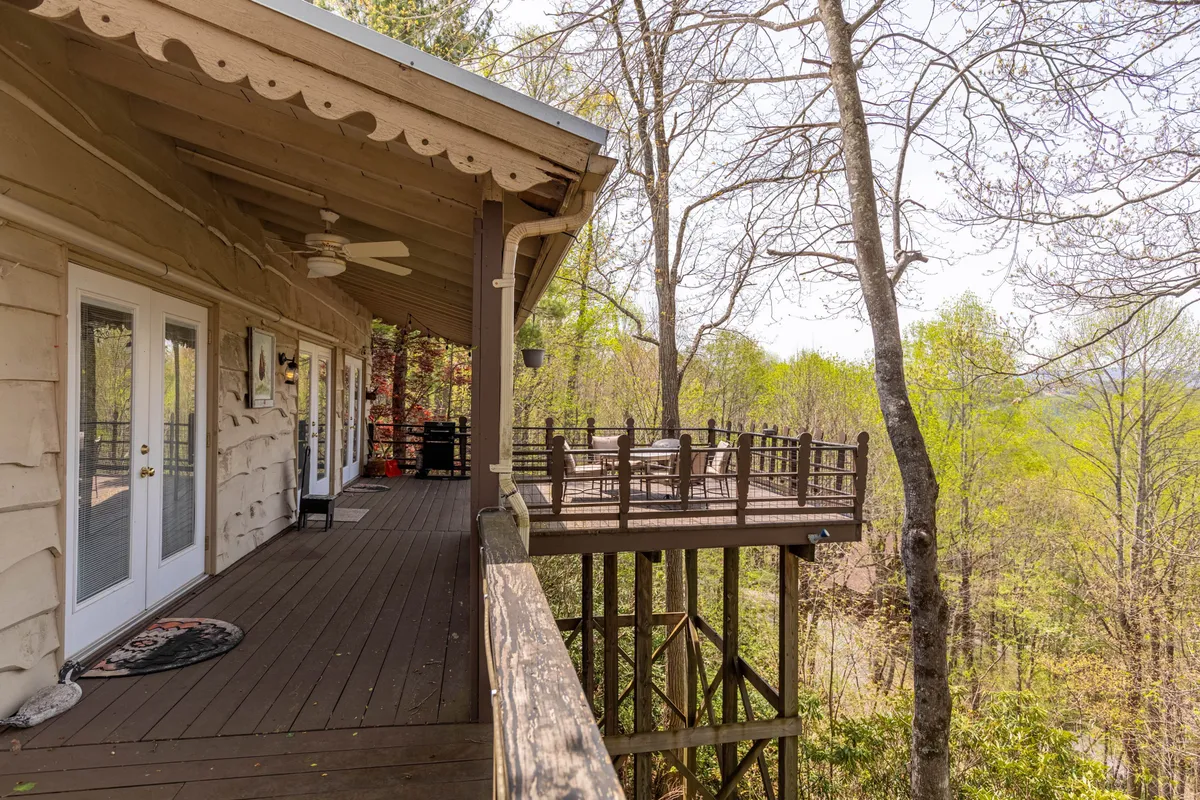 A secluded wooden deck enveloped by trees and natural views, featuring comfortable rocking chairs. The tranquil setting is ideal for quiet mornings or peaceful evening reflections, mirroring the suite's description of its private outdoor space.