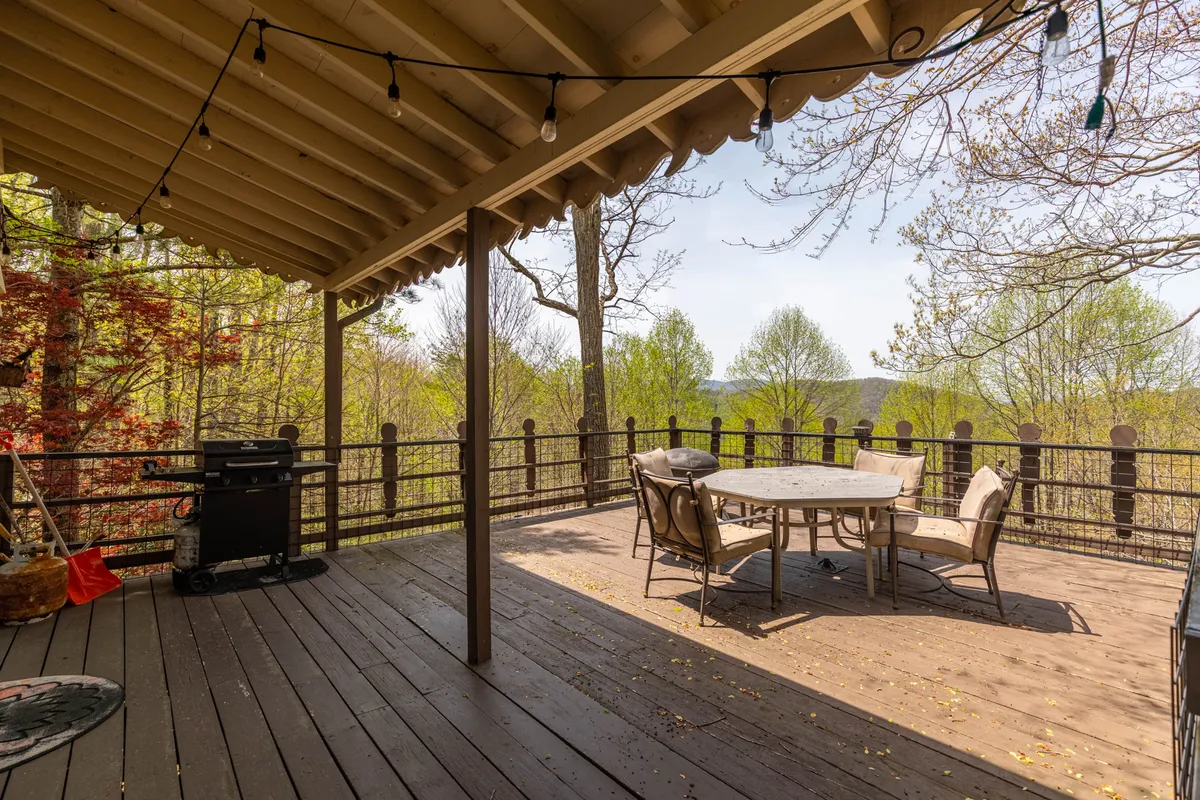 An outdoor dining area is nestled among trees, complete with a large table and grill, inviting families to dine and relax outside. The area captures the mountain ambiance, with twilight light hinting at sunset views and starlit evenings.